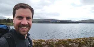 Alumnus David August with a loch in the background