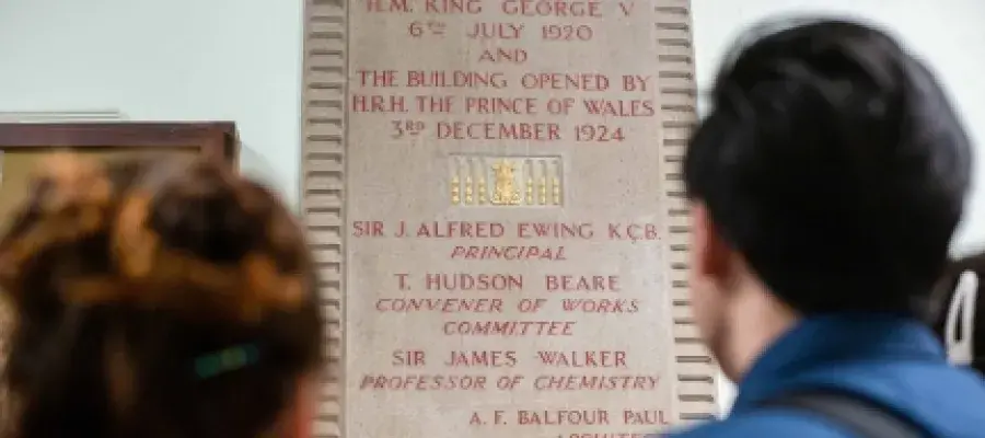 People reading a plaque on a wall