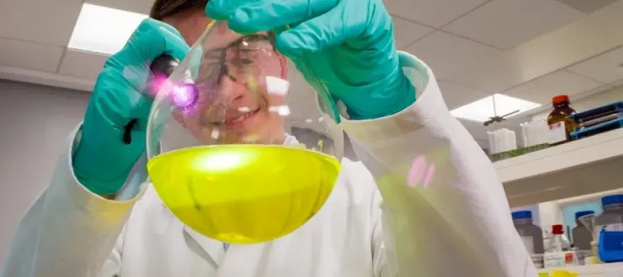 Researcher holding a flask of yellow liquid
