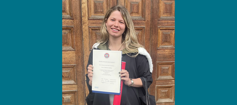 Alumna Grace Gubbay standing outside of the McEwan Hall with degree certificate