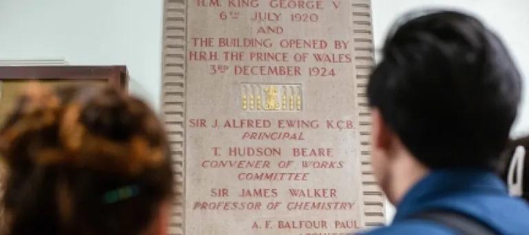 People reading a plaque on a wall