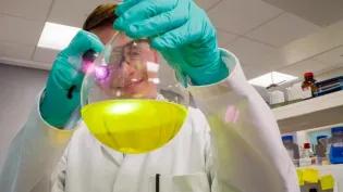 Researcher holding a flask of yellow liquid