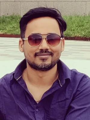 Image of a man smiling with sunglasses and a dark polo shirt on.